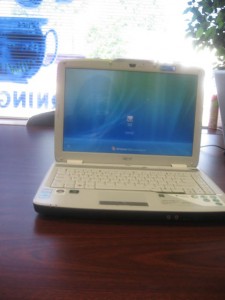 Open white laptop on wooden table by window